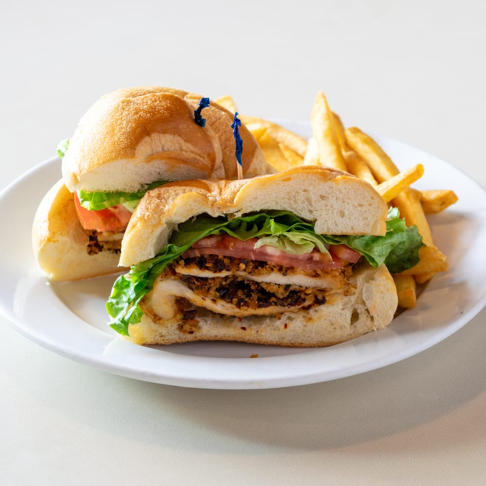Two sandwiches with lettuce and tomato, served alongside golden French fries on a white plate.